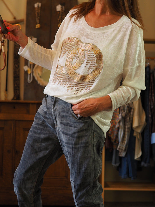 Blouse blanche effet pan de velours. Motifs dorés et strassés.
70% Viscose 25% Nylon 5% Elasthane.
Taille unique convient du 36 au 42.
Tour de poitrine 120cm Longueur dos 70cm.