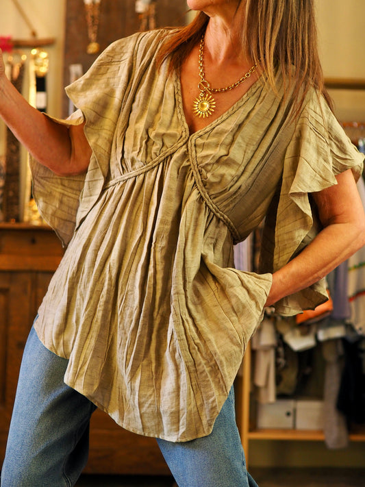 Blouse effet froissé kaki. Manches volants. Resserrable à la taille avec cordon dans le dos.
60% Viscose 20% Lin 20% Nylon.
Taille S-36/38 et M-38/40