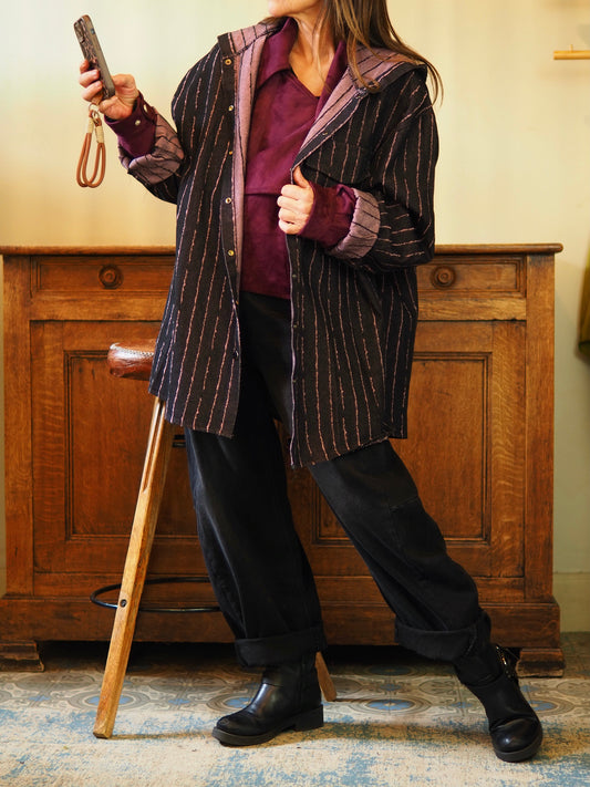 Veste chemise jeans noir avec une fine ligne irrégulière vieux rose. Boutons pressions et capuche.
Taille unique convient du 36 au 46.
75% Coton 25% Polyester.
Tour de poitrine 148cm Longueur dos 85cm.