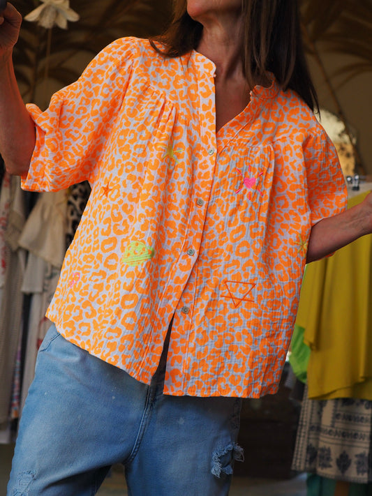 Blouse leopard fluo orange. Motifs brodés.

100% Coton. 
Taille unique convient du 36 au 44.
Tour de poitrine 140cm Longueur dos 66cm.
