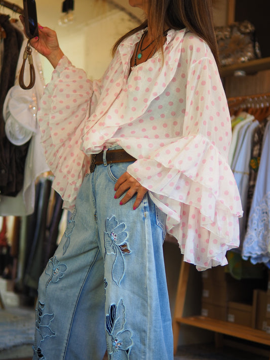 Blouse fluide blanche à pois roses, avec volants romantiques et manches évasées. Légère et féminine, idéale pour un look chic bohème.

Taille unique du 36 au 42.
100% Coton.
Tour de poitrine 126cm Longueur dos 63cm.