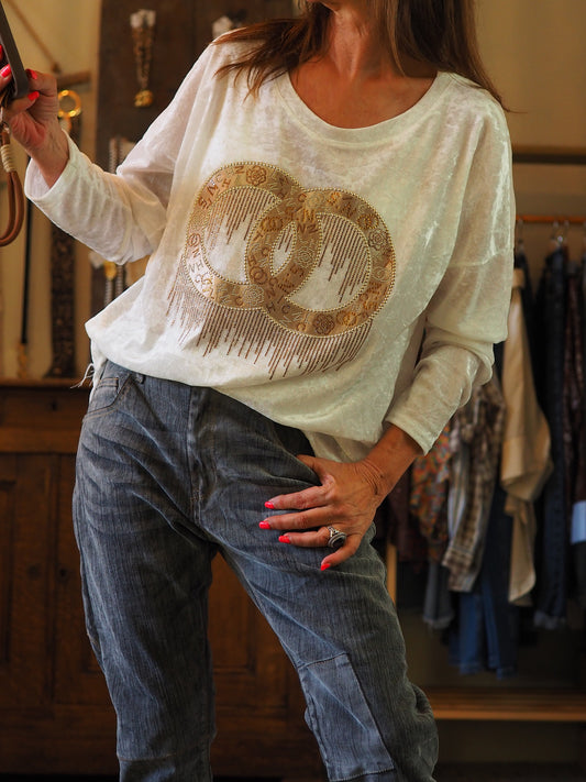 Blouse blanche effet pan de velours. Motifs dorés et strassés.

70% Viscose 25% Nylon 5% Elasthane.
Taille unique convient du 36 au 42.
Tour de poitrine 120cm Longueur dos 70cm.