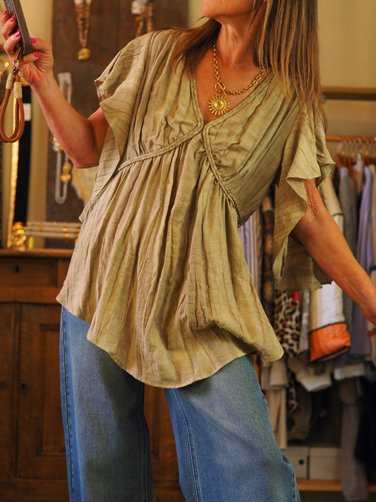 Blouse effet froissé kaki. Manches volants. Resserrable à la taille avec cordon dans le dos. 

60% Viscose 20% Lin 20% Nylon.
Taille S-36/38 et M-38/40