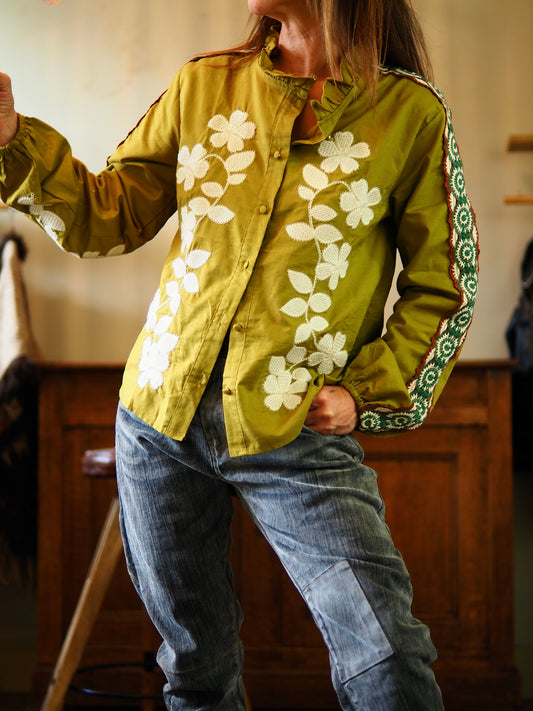 Blouse couleur olive avec broderies à l'avant et broderies vertes et rouilles sur les manches.

Taille S/36 M/38 L/40 
45% Chanvre 55% Coton.
Mesures :
 S/36 : Tour de poitrine 106cm.

M/38 : Tour de poitrine 110cm.

L/40 : Tour de poitrine 114cm.