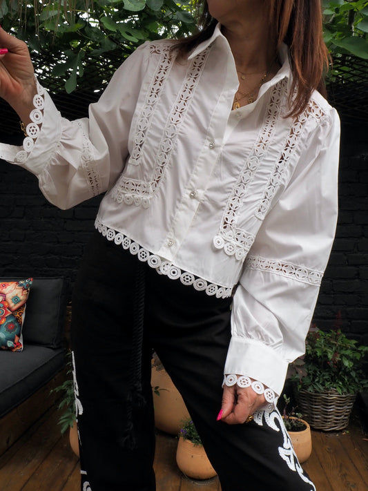 Chemise courte blanche avec broderies et boutons en strass.  65% Polyester 35% Coton. Taille unique convient du 36 au 38/40 Largeur aisselle à aisselle 56cm Longueur dos 46cm.