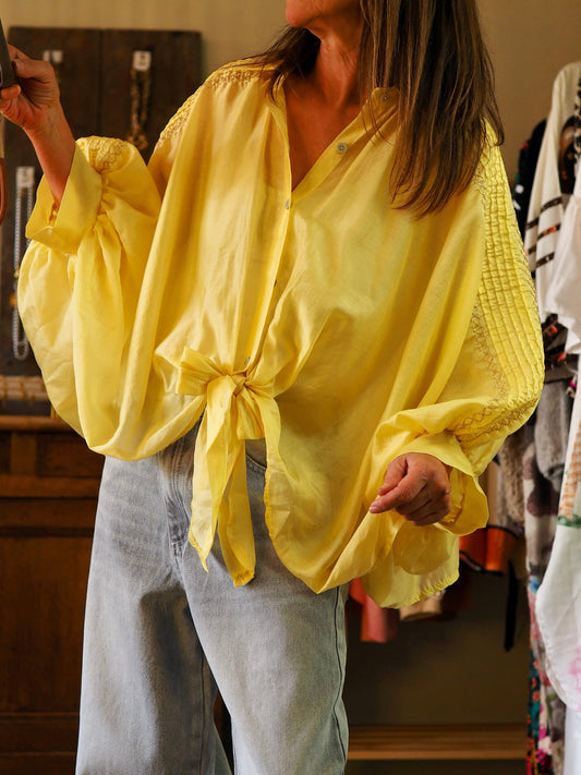 Chemise ample jaune à nouer devant. Coupe chauve-souris. Fils dorés sur les manches.

85% Tencel 15% Polyester.
Taille unique convient du 36 au 46.
 Longueur dos 60cm.