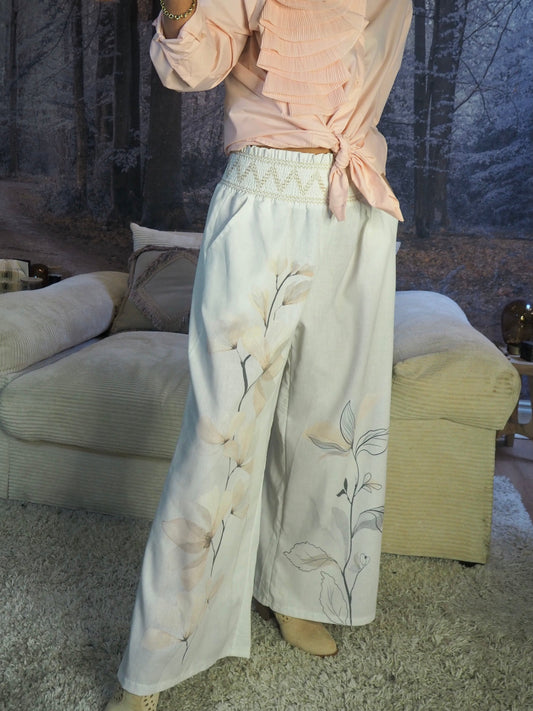 Pantalon blanc avec motifs fleuris dans les tons roses/saumons pâles. Taille grand élastique brodé. 70% Lin 30% Polyester. Taille Unique du 36 au 40. Tour de taille maximum 104cm.