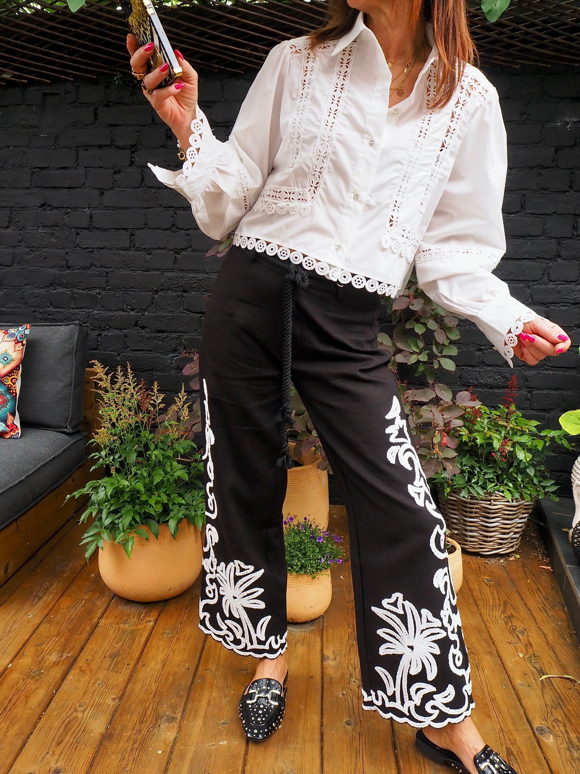 Pantalon noir avec broderies blanches. Ceinture en cordon fournie avec.  55% Coton 45% Lin. Taille S/36 M/38 et L/40.