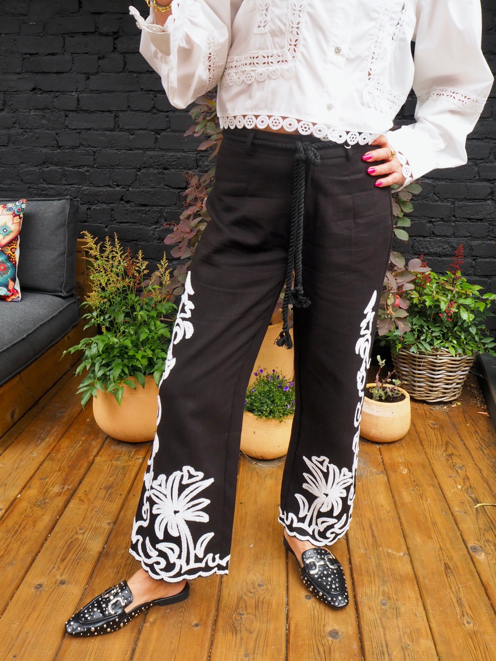 Pantalon noir avec broderies blanches. Ceinture en cordon fournie avec.  55% Coton 45% Lin. Taille S/36 M/38 et L/40.