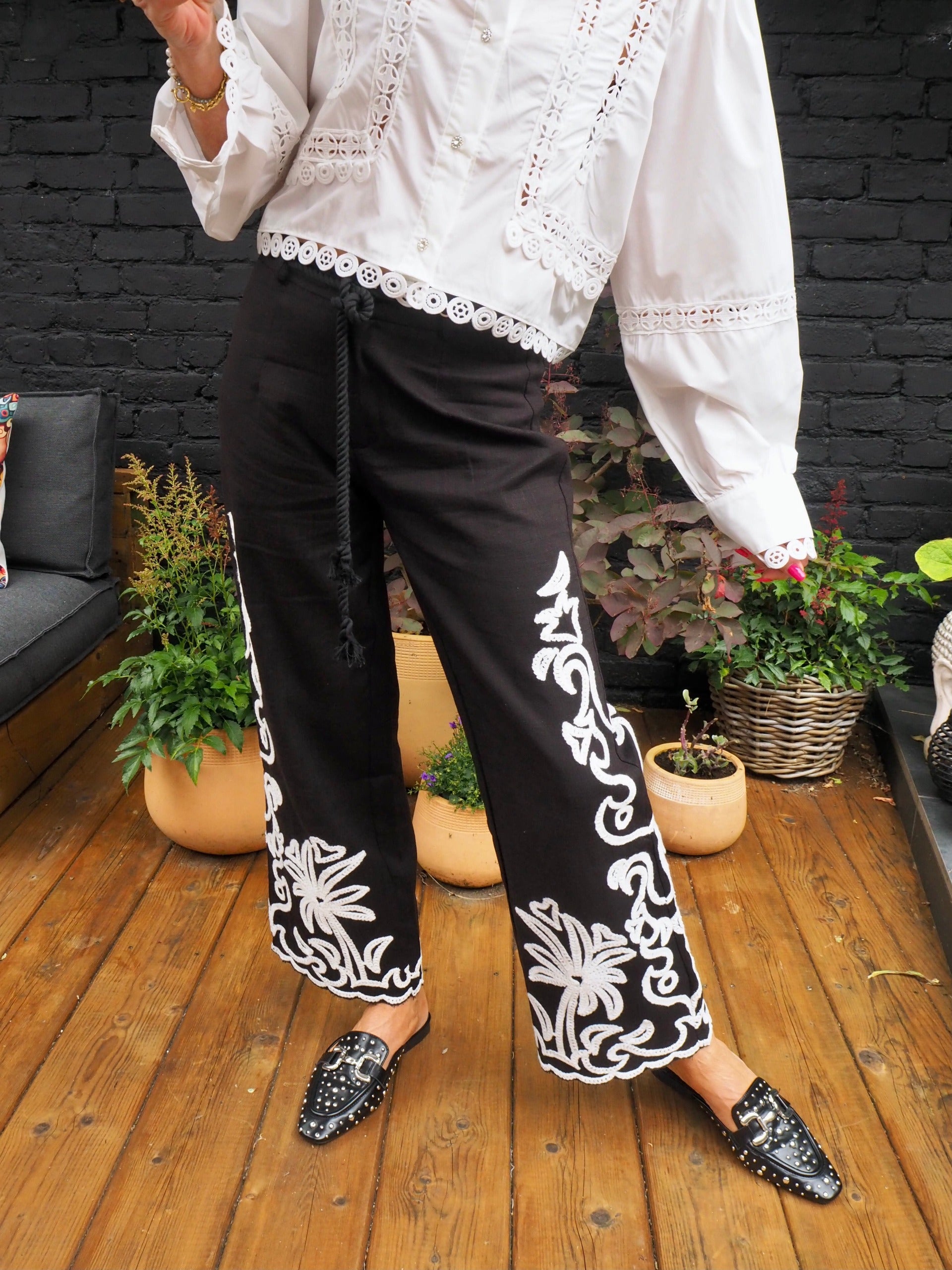 Pantalon noir avec broderies blanches. Ceinture en cordon fournie avec.  55% Coton 45% Lin. Taille S/36 M/38 et L/40.
