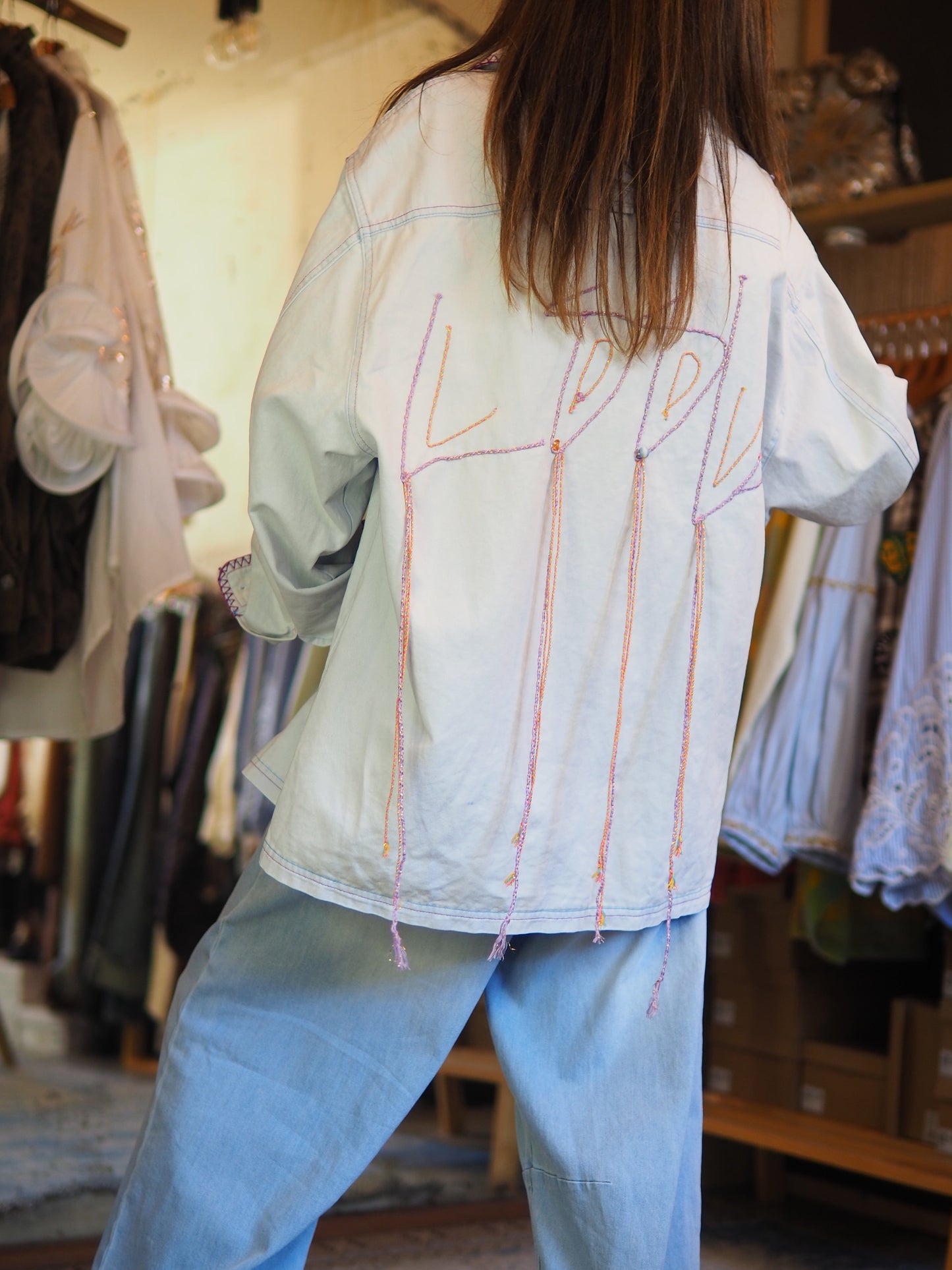 Veste oversize bleu clair avec broderies oranges et parmes au dos et finitions contrastées. Originale et tendance, parfaite pour twister un look casual.&nbsp;

Taille unique du 36 au 42/44.
90% Coton 10% Polyester.
Tour de poitrine 124cm Longueur dos 78cm.