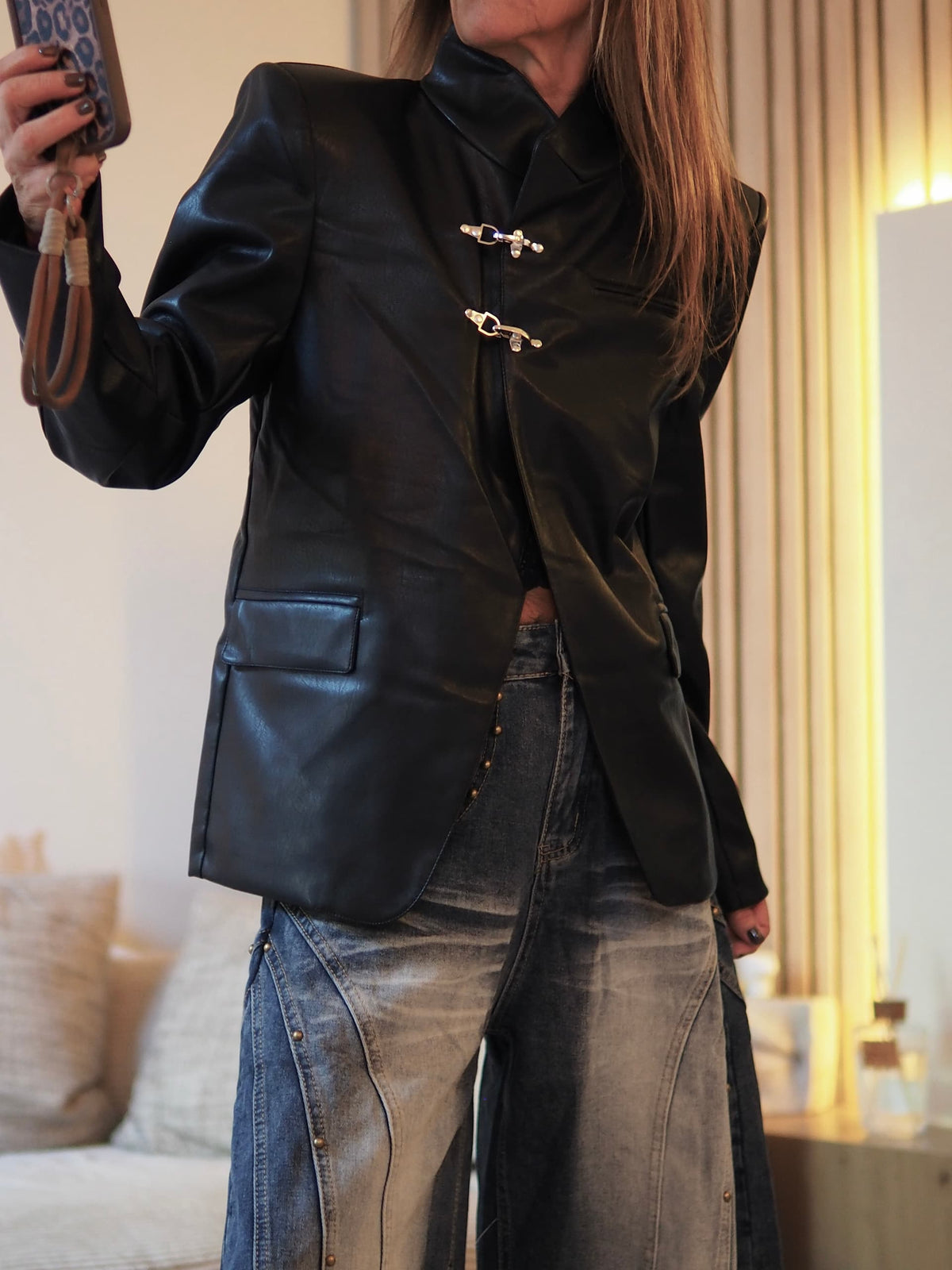 Veste simili noir avec attaches métaliques.